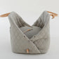 Ruby Max & Minette, A gray, quilted dog carrier or pet bed with leather accents and adjustable straps.