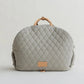 A gray, quilted dog carrier or pet bed with leather accents and adjustable straps.